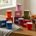 Colorful fine bone china Java mugs on a wooden surface with gift boxes.