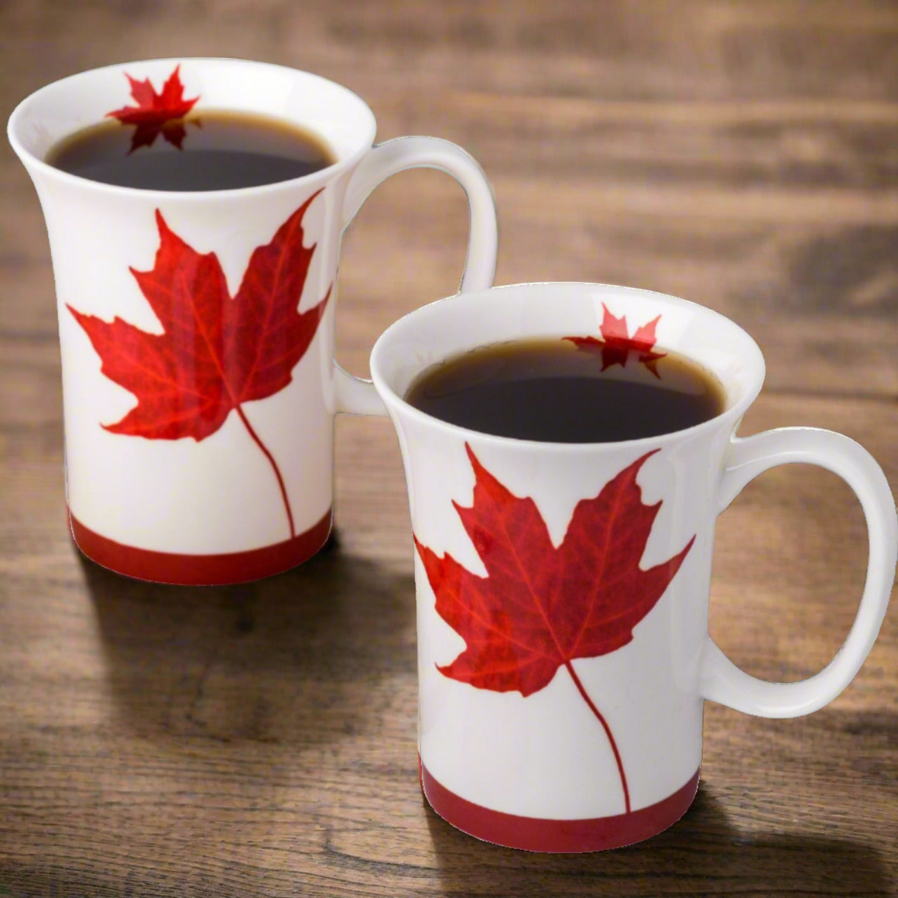 Two Crest mugs with the Canadian design filled with coffee on a wooden table. 