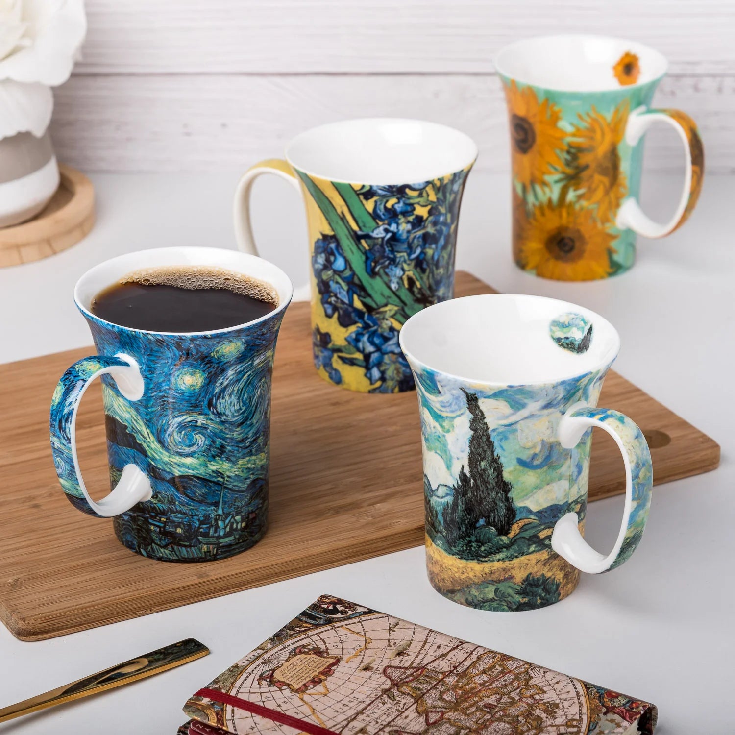 Gustav Klimt's the kiss artwork featured on a pair of fine bone china crest mugs filled to their 11oz capacity with fresh brewed coffee sat on a white stone countertop with books and aromatics in the background.