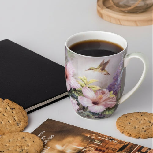 Mug with hummingbird design by Lena Liu on countertop with cookies